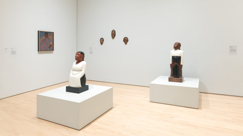 An SFMOMA gallery shows various works including wooden sculptures by artist Sargent Johnson, and a painting by artist Carlos Mérida.