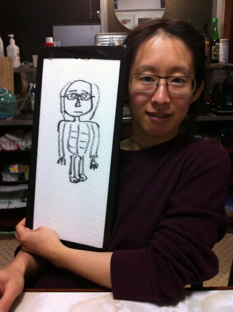 Portrait of Lieko Shiga holding up a drawing.