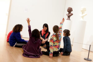 Children and a docent sitting on the floor of a gallery