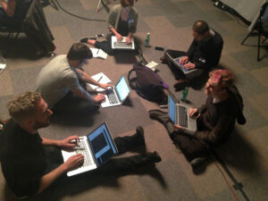 A group sitting on the floor, working on laptops