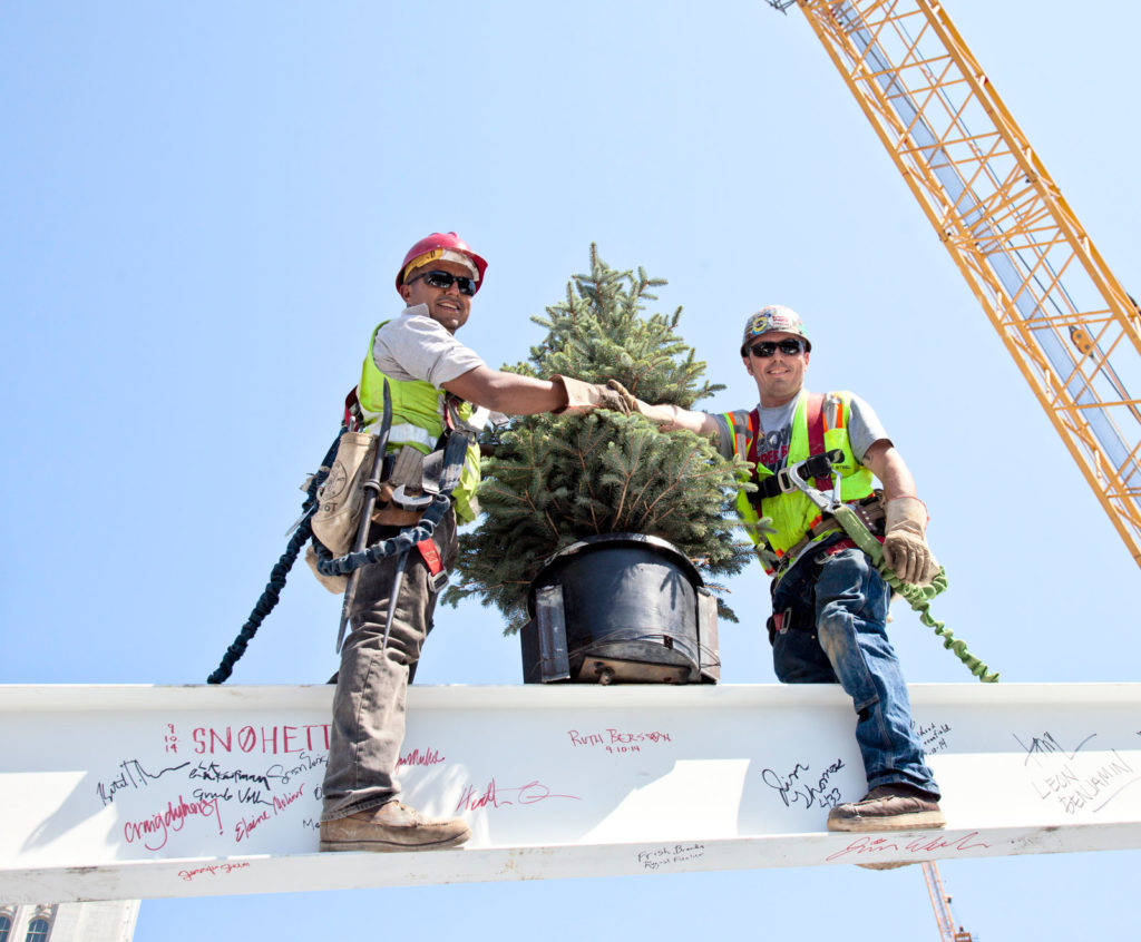Construction workers install a tree at the topping out ceremony