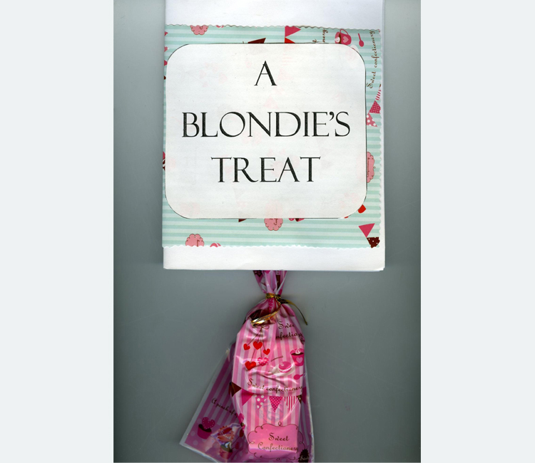 "A Blondie's Treat" appear in black letters on a white label over wrapping paper with a pink candy bag hanging below 