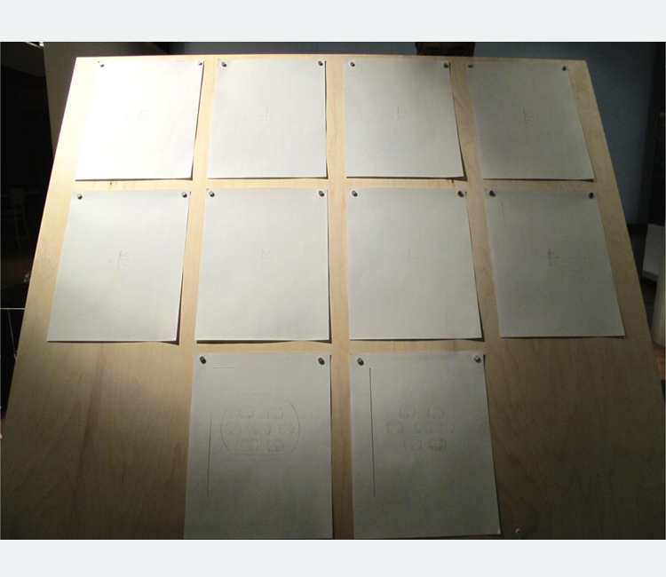 Ten hand drawings on white paper tacked to a wooden board