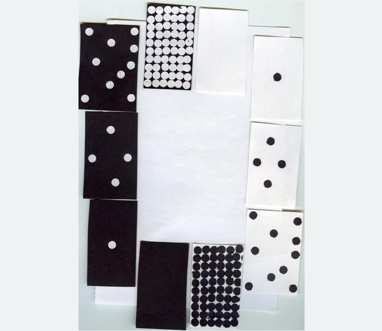 An assortment of handmade black and white paper dominoes with irregular dots
