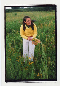 A woman picks yellow wildflowers in a meadow