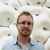 Man in glasses standing in front of white wall made of pillowy, hexagonal modules