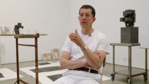Artist Antony Gormley in his studio, with sculptures made up of cubic forms in the background