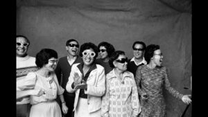 A black and white photograph of a large Asian-American family, caught in a spontaneous moment in a party photo booth