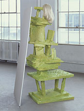 green sculpture with blonde wig in front of windows
