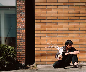 Jeff Wall; man sitting in front of brick wall holding spilling beverage