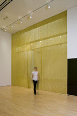 installation shot of person walking in front of golden wall 