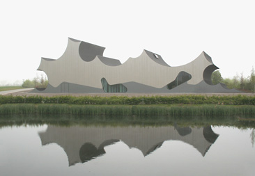 J. Mayer H, sculptural building on grass in front of reflective lake