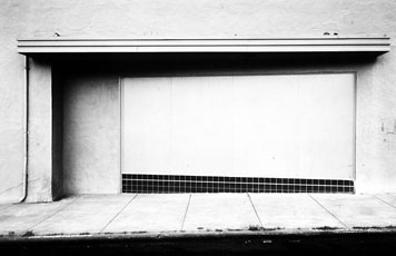 Lewis Baltz, black and white photo of sidewalk and street wall