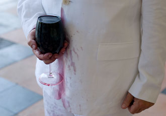Dennis Adams, man holding wine glass spilling on white coat