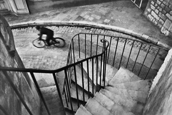 Cartier-Bresson, perspectival photo of stairwell leading to man on bicycle on street