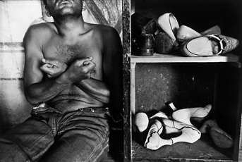 Cartier-Bresson, image of man's torso sitting down next to cubbies filled with shoes