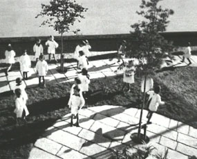 David Claerbout, video still, school children standing in courtyard with two small trees