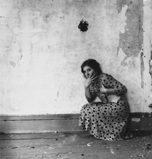 Woodman; photo of woman in polka dot dress leaning against decrepit wall