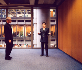 Carey Young, video still with man and woman standing in office room