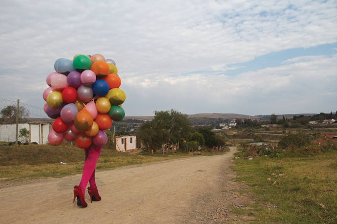 colorful balloons and legs in pink stockings walking down dirt path