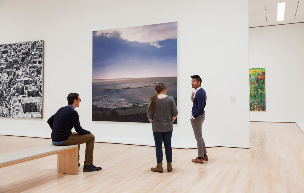 Three people looking at an artwork.