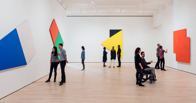 A group of people looking at paintings by Ellsworth Kelly