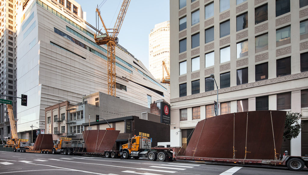 Large bronze sculptural coils are transported along a city street