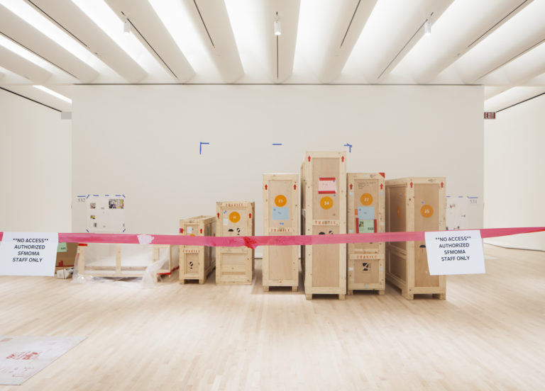 Crates sit behind a red rope in an empty gallery