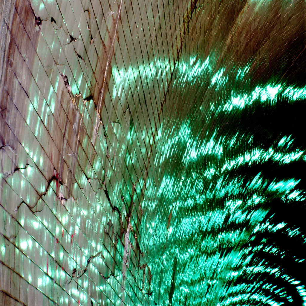 Reflection of water and green lights on the ceiling of a tunnel.