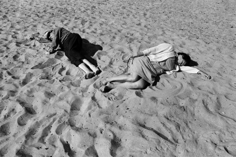 Two people lay in the sand 