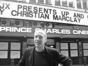Christian Marclay stands in front of a theater marquee bearing his name