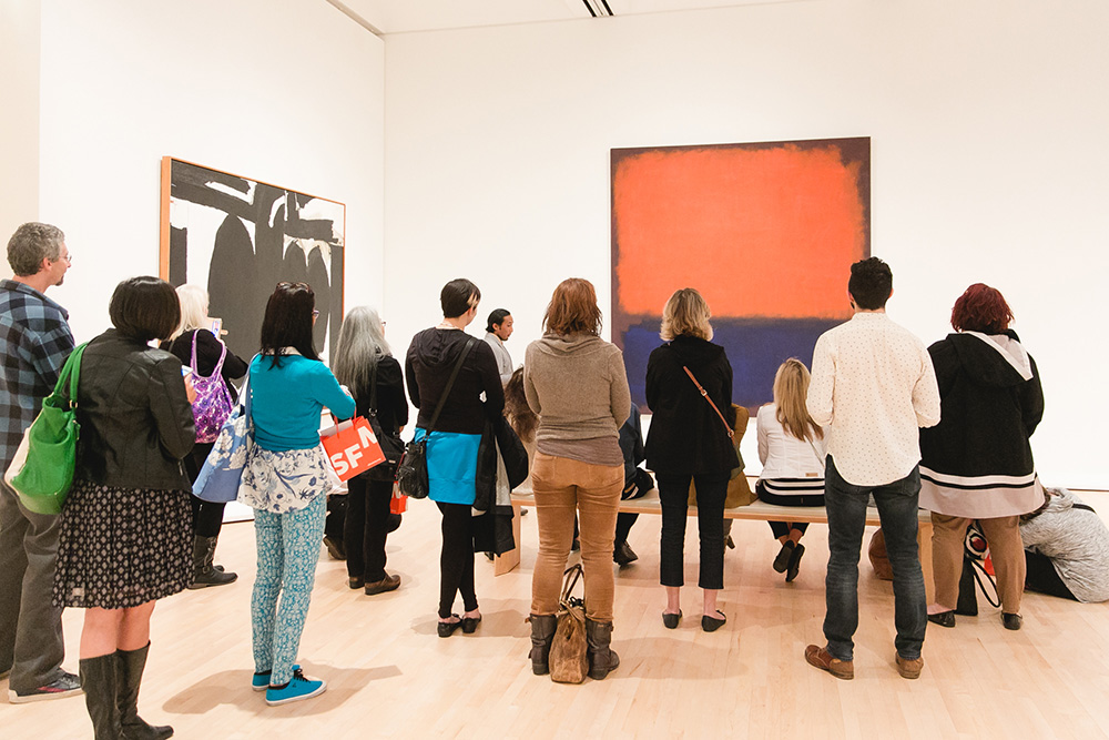 A group of people gathered around a large painting