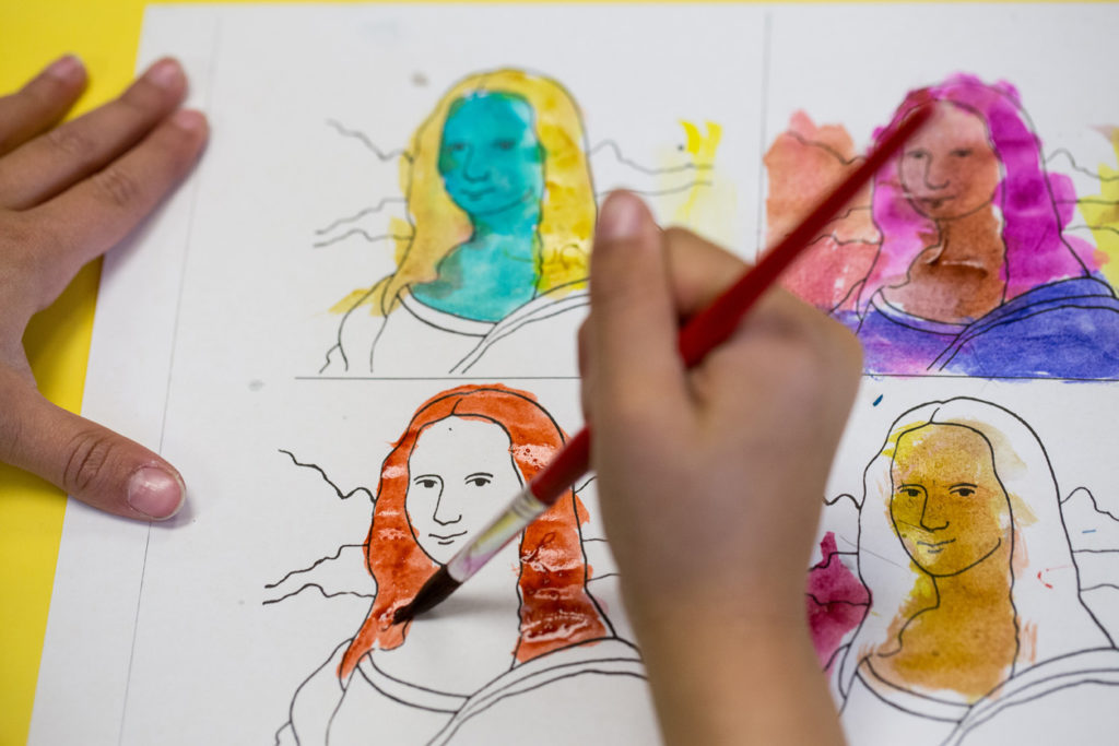 A child's hands paint a series of outlines of the Mona Lisa's face