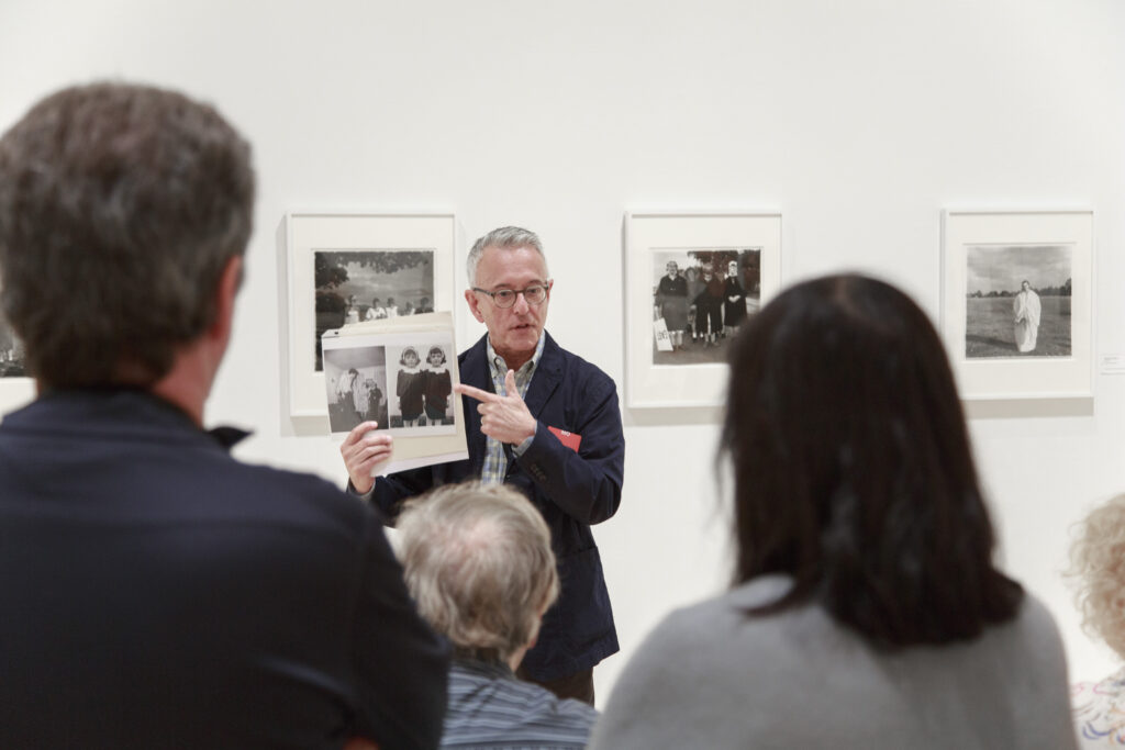 A museum guide holds a copy of a Diane Arbus photograph