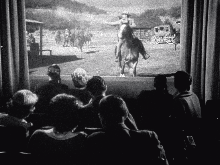 A film still featuring an audience watching an old time western movie
