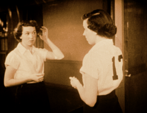 A Caucasian woman with short brown hair looks at herself in the mirror