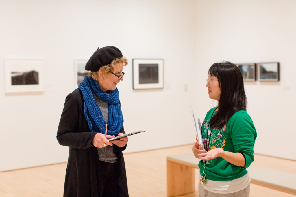 Two smiling women look at each other in the gallery