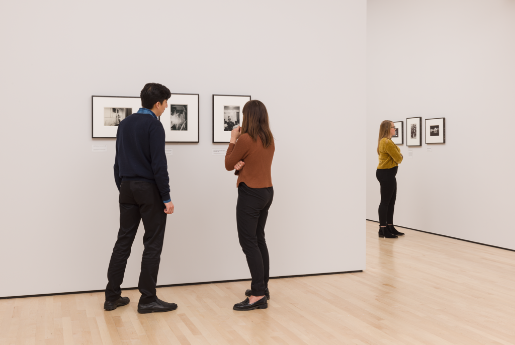 Three visitors looked at small black and white photographs in the diane arbus exhibition