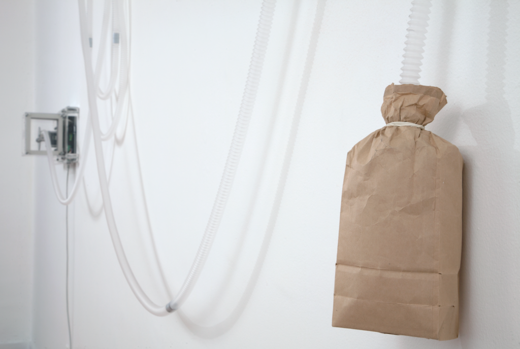 A brown paper bag tied with string hangs on a white wall, Lozano-Hemmer Soundtracks