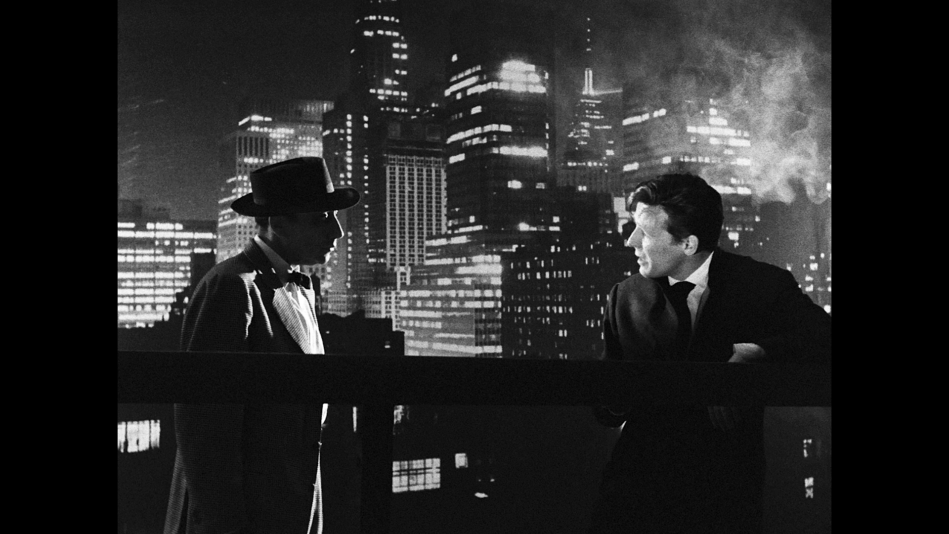 Two men at night with the New York skyline behind them