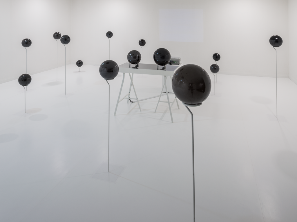 A white room filled with dark spheres mounted on sticks, Yagi Soundtrakcs