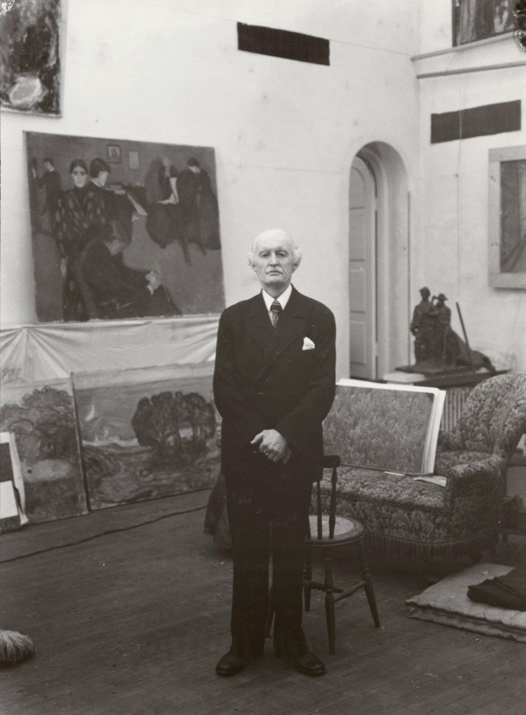 Black and white portrait of an elderly Caucasian man wearing a suit surrounded by paintings, Edvard Munch