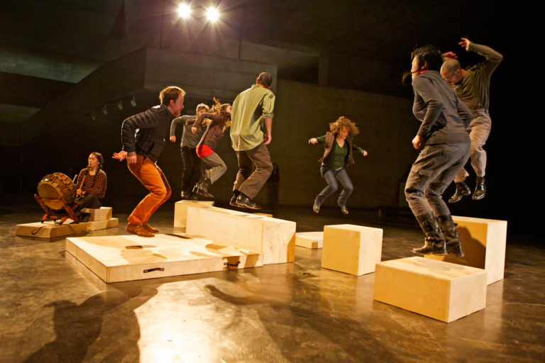 A group of figures move around wooden blocks, Anna Halpern Soundtracks
