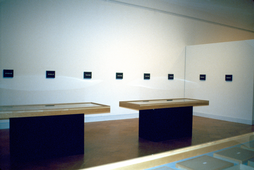A row of small black blocks featuring white lettering hanging in a gallery