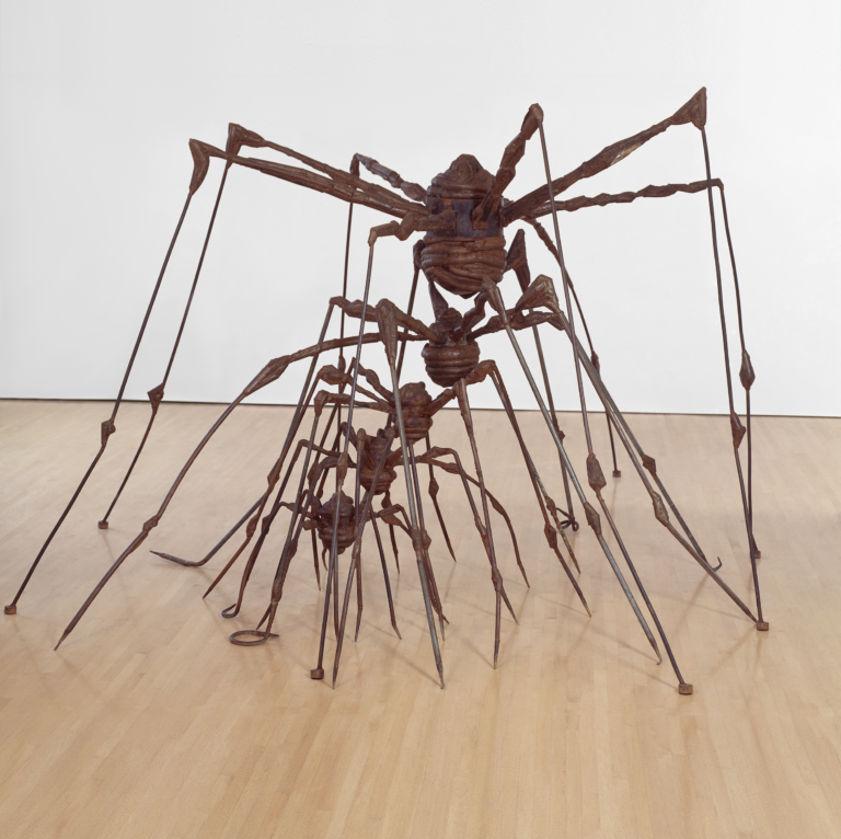 A large metal sculpture of a spider with smaller metal spider sculptures nested between its legs