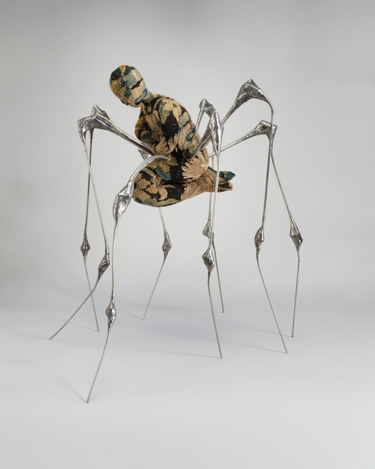 A sculpture with sliver legs and a fabric body shaped like a kneeling human