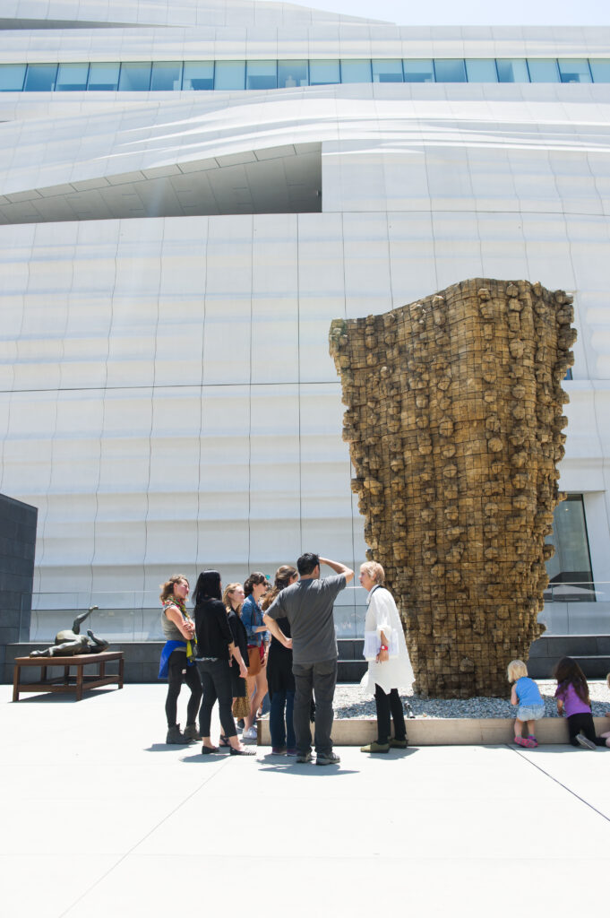 A tour group in front of a large wooden sculpture on SFMOMA's sculpture terrace