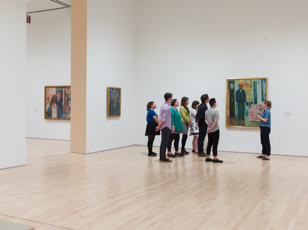 A tour group standing in front of Edvard Munch's self-portrait Between the Clock and the Bed