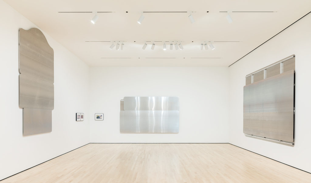 A gallery hung with large aluminum panels