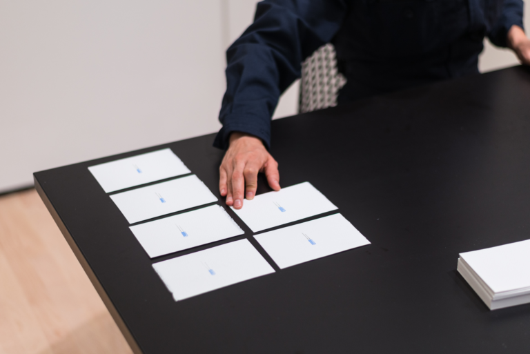 A hand arranges rectangular white cards on a black table, Munoz, Sountracks
